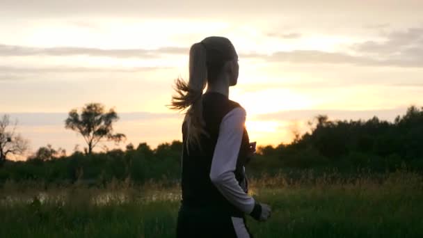 夕日の前の川の近くの夕暮れ時にジョギングを実行する女性 夕方田舎の田園風景 雨雲天気春の季節 2倍スローモーション Fpsの1 2スピード — ストック動画