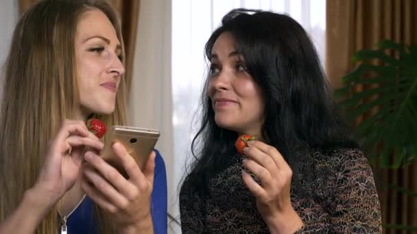 Deux Amies Mangent Des Fraises Tout Discutant Regardant Les Médias — Video