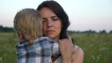 Anneyi Seven, Seven, Sevimli Küçük Oğul Kucaklayan Mutlu Anne. Aile Güzel Doğa 'ya Dinleniyor. Günbatımı Güneş Işıkları. Akşam Kırsal Sahne. 2x Slow motion - Yarı hız 60 FPS