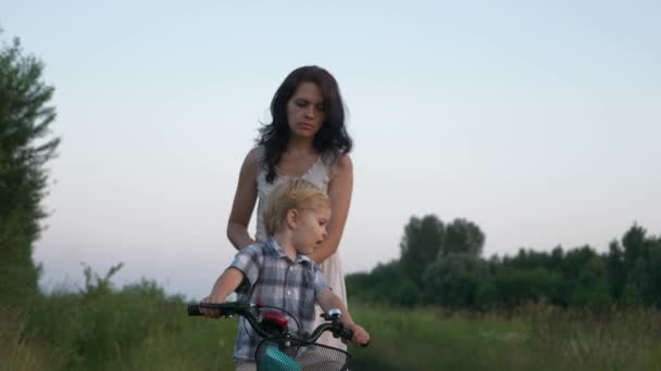 Little Boy Aprende Andar Bicicleta Infantil Com Ajuda Jovem Mãe — Vídeo de Stock