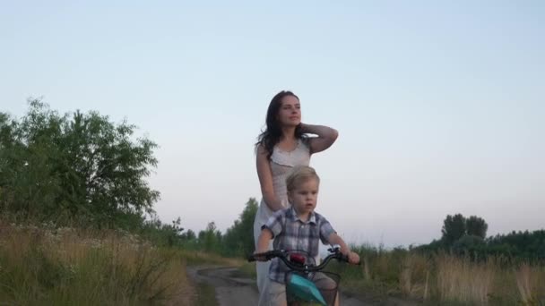 Little Boy Aprende Andar Bicicleta Infantil Com Ajuda Jovem Mãe — Vídeo de Stock