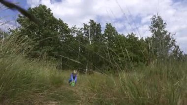 High Grass Field 'da oynayan neşeli küçük çocuk. Parlak Güneşli Yaz Günü