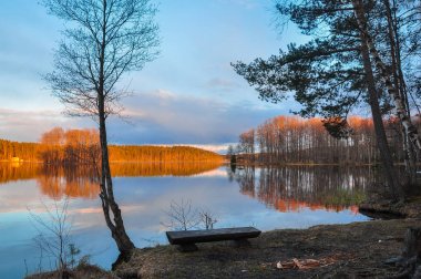 Sakin manzara. Göl günbatımı. Sahilde ahşap Bank