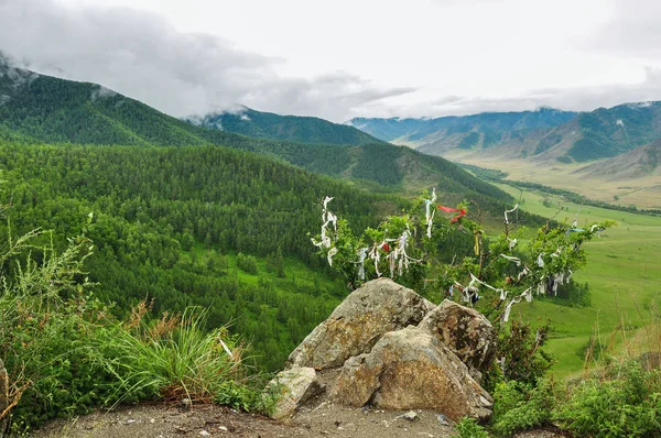 Pierre et buisson, accrochés à des rubans contre le paysage d'une vallée de montagne. Col de route Chike-Taman, Altaï — Photo