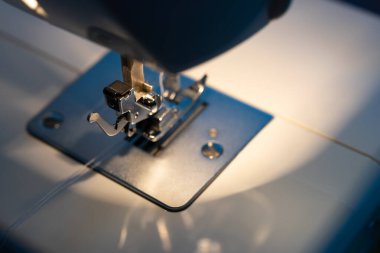 Dikiş makinesi üzerinde çalış. Beyaz kumaş, beyaz iplik. 