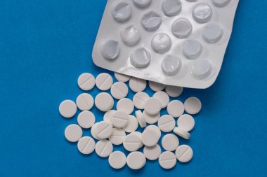 Kabarcık ve beyaz tabletler mavi arka plana saçılmış.