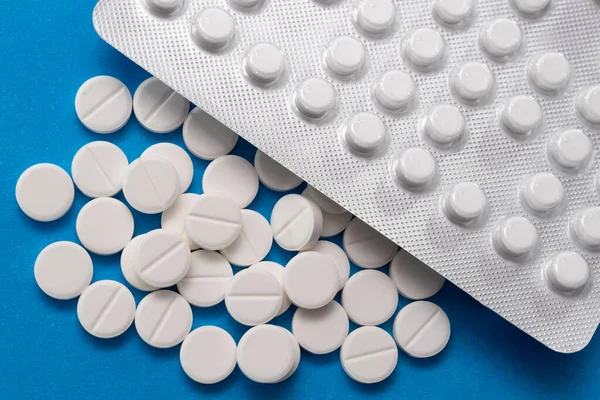 Kabarcık ve beyaz tabletler mavi arka plana saçılmış.