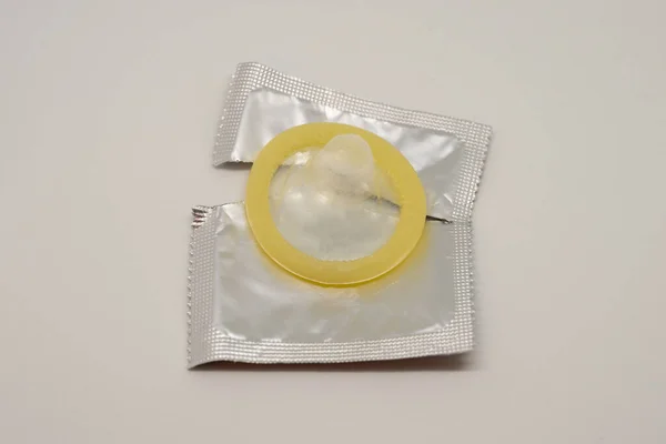 Yellow open condom on a white background