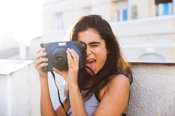 Femeie cu limba afară ţinând camera foto — Fotografie, imagine de stoc