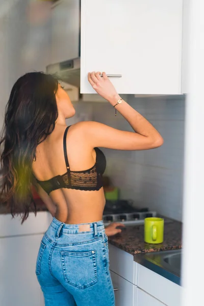 Female standing in kitchen opening cupboard — Stock Photo, Image