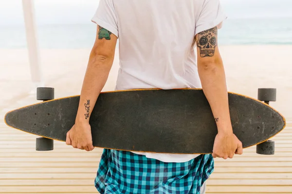 Tetovaný muž, který držel skateboard — Stock fotografie