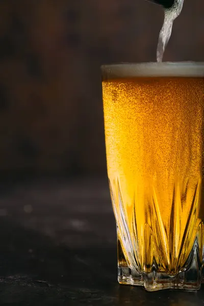 Pouring beer into a glass on dark — Stock Photo, Image