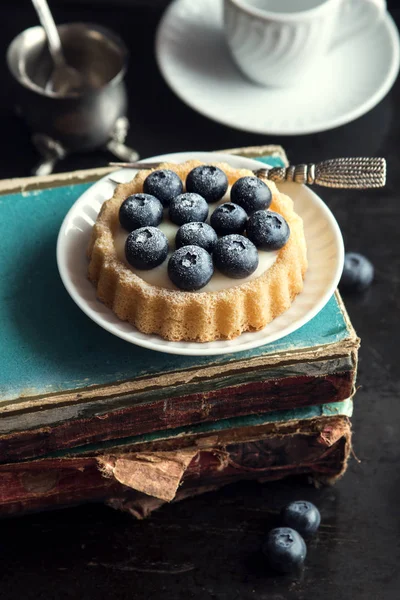 Blueberries cake over old books — Stock Photo, Image