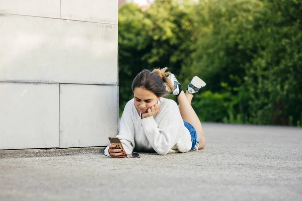 Girl browsing phone while lying on ground — Stock Photo, Image