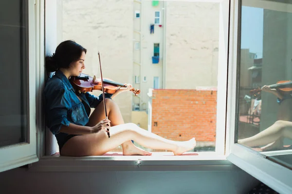 Mulher romântica tocando violino no peitoril da viúva — Fotografia de Stock