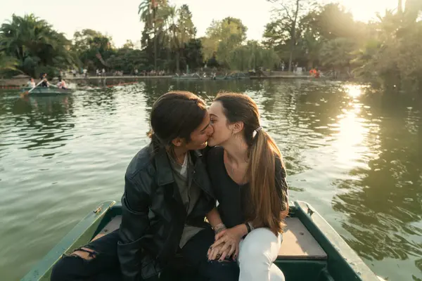 坐在小船和亲吻在公园湖的年轻夫妇的前面看法 — 图库照片