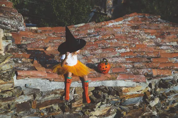 Chica en traje de Halloween sentado en el techo — Foto de Stock