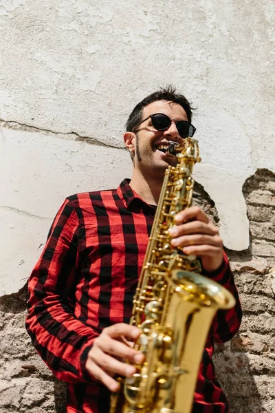 Man leaning on wall and playing saxophone — Stock Photo, Image