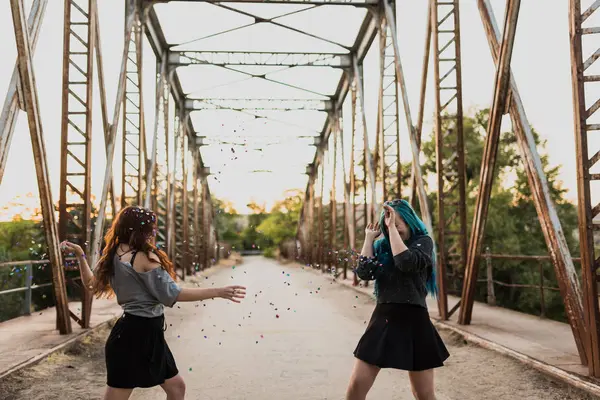 Meisjes gooien van confetti op brug — Stockfoto