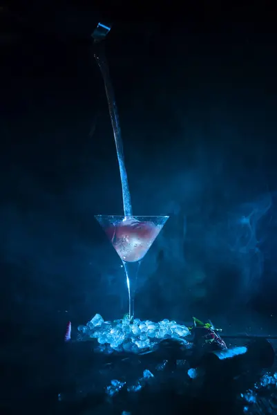 Copo de cocktail em cubos de gelo enquanto verte — Fotografia de Stock