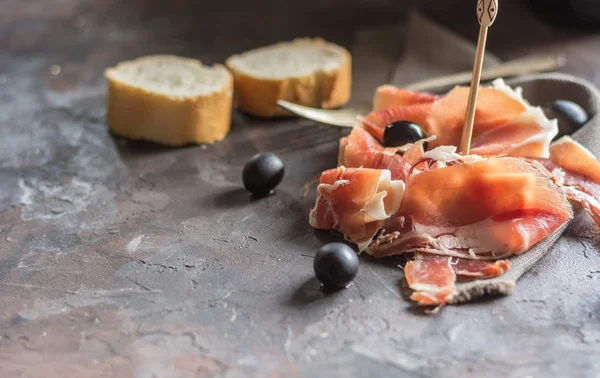 Gerookte ham met brood en olijven — Stockfoto