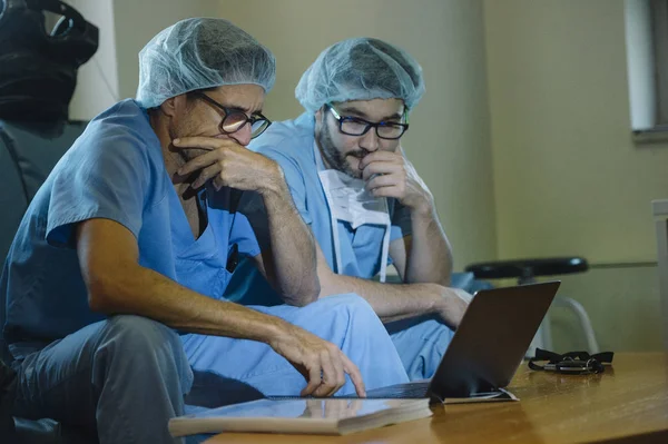 Sidovy Två Män Medicinsk Enhetliga Tittar Förbryllat Medan Tittar Laptop — Stockfoto