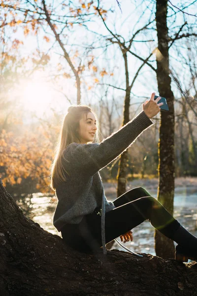 Side View Woman Sitting Tree Trunk Taking Selfie Smartphone Fall — Stock Photo, Image