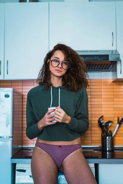 カップに自宅の台所で立っているパンツの若い女性 — ストック写真