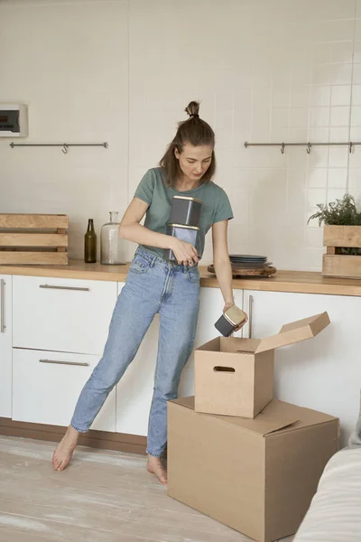 Çıplak Ayaklı Kadın Mutfaktaki Karton Kutulardan Metal Kaplar Taşıyor — Stok fotoğraf