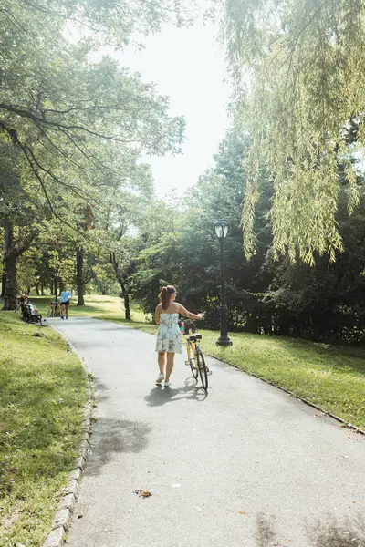 Casual lady wheeling bicycle at beautiful park — Stock Photo, Image