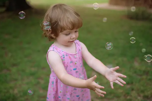 Van Boven Schattig Kind Roze Jurk Lachen Vangen Regenboog Zeepbellen — Stockfoto