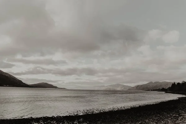 Empty Wavy Water Washing Dark Shore Surrounded Mountains Gray Cloudy — ストック写真