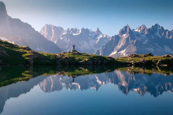 Eenzame Toerist Heuvelachtige Oever Reflecterend Kristalmeer Besneeuwde Bergen Zonlicht — Stockfoto