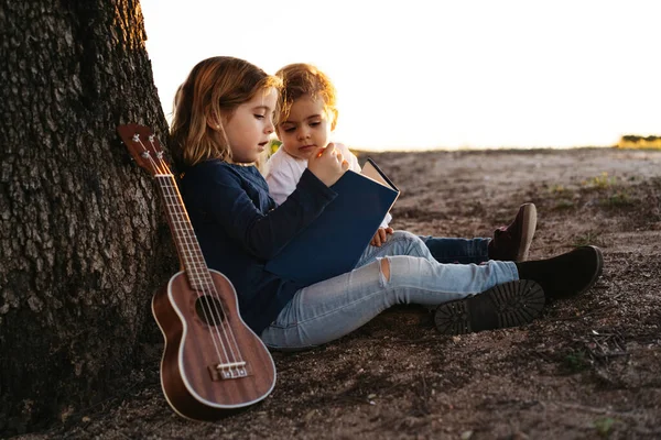 Vista Lateral Adorable Niña Leyendo Interesante Historia Hermano Menor Mientras — Foto de Stock