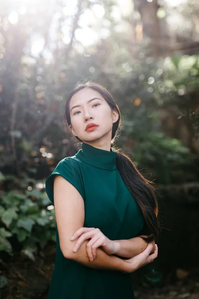 Młoda Azjatycka Kobieta Modnej Sukience Zielonych Krzakach Patrząc Aparat Fotograficzny — Zdjęcie stockowe