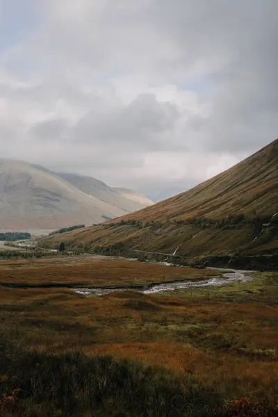 Szkocki Krajobraz Wąską Zakrzywioną Rzeką Płynącą Wśród Porośniętych Trawą Wzgórz — Zdjęcie stockowe