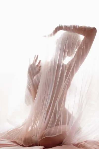 匿名の裸のモデルは 明るい日差しに対してカーテンの透明なプリーツ生地で覆われています — ストック写真