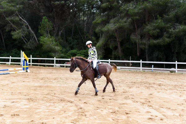 十代の男の子ジョッキーでヘルメット乗馬茶色の馬上の馬場馬術学校での訓練中に — ストック写真