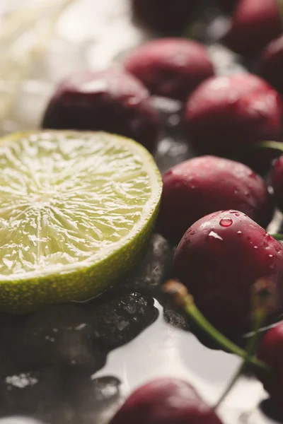 Cerejas vermelhas e metade limão — Fotografia de Stock
