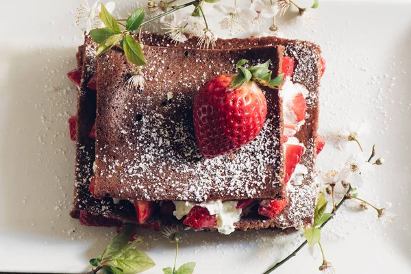 Directamente por encima de la vista de la tarta de fresa casera y ramitas en flor - foto de stock