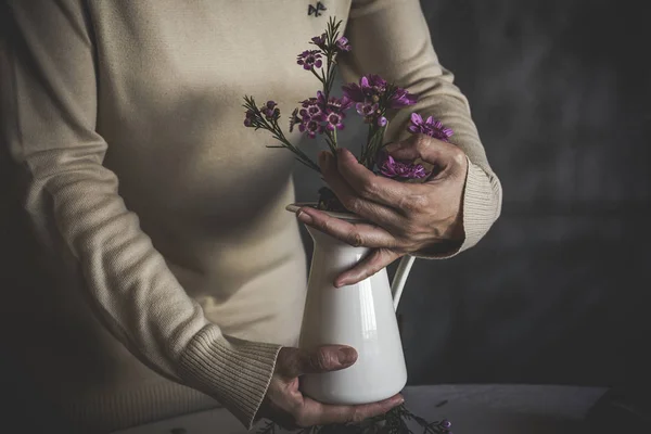 Закройте вид на женские руки, держащие вазу с ветвями розовых цветов — стоковое фото