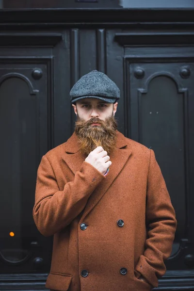 Portrait d'un homme barbu réfléchi regardant la caméra et tenant la barbe — Photo de stock