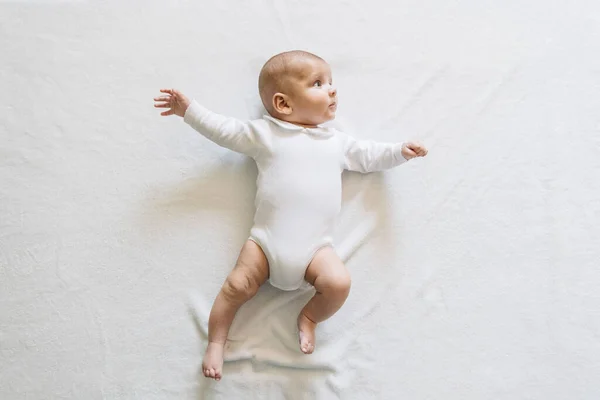 Vue Du Dessus Du Joli Bebe En Pyjama Blanc Avec Bouche Ouverte Couchee Sur Le Lit Bras Et Jambes En Mouvement Levant Les Yeux Curieux Mignon Stock Photo