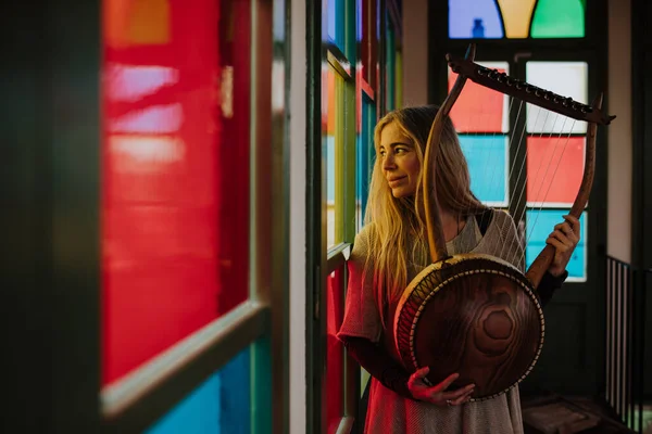 Woman with lyre standing near stained glass windows — Stock Photo