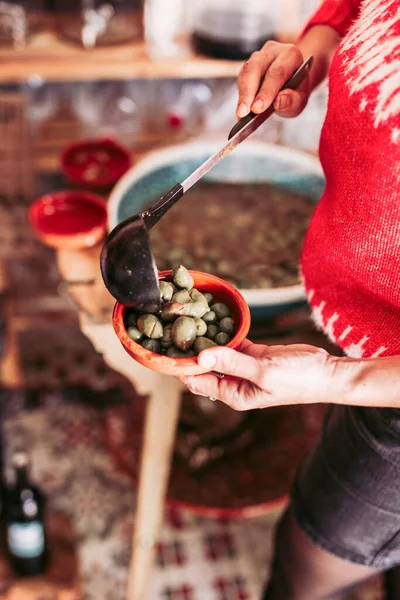 Unbekannter steckt Schöpfkelle mit Oliven in Schüssel, während er in Lebensmittelgeschäft arbeitet — Stockfoto