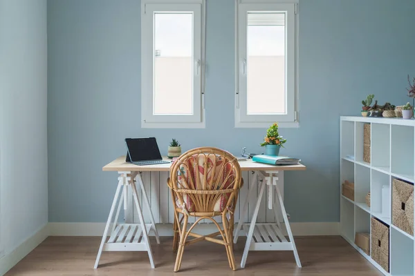 Interieur des modernen Zimmers und Arbeitsplatzes mit Holztisch mit Laptop und Mappe und weißerem Stuhl in der Nähe von Holzregalen mit Kästen und Topfpflanzen — Stockfoto
