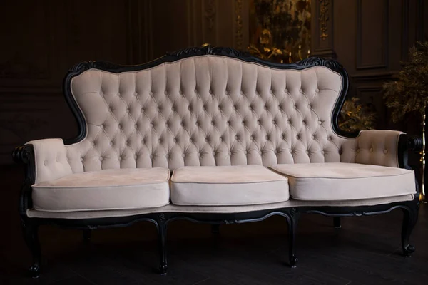 Antiguo sofá beige en una habitación oscura con un espejo vintage . —  Fotos de Stock