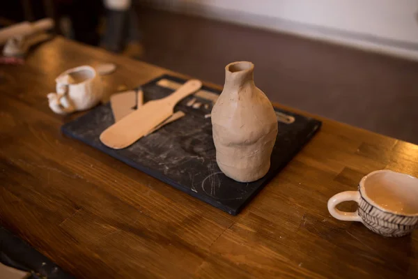 A master class in modeling a clay jug. Table with clay and a tool for creativity. — Stock Photo, Image