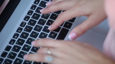 Öğrenci dönem ödevi bir dizüstü bilgisayarda yazıyor. Güzel manikür bir kızla.