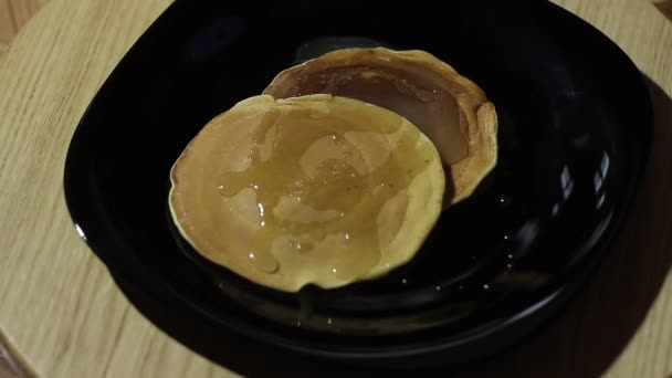 Två pannkakor Twist på en svart plåt. Pannkakor täckt med honung. — Stockvideo